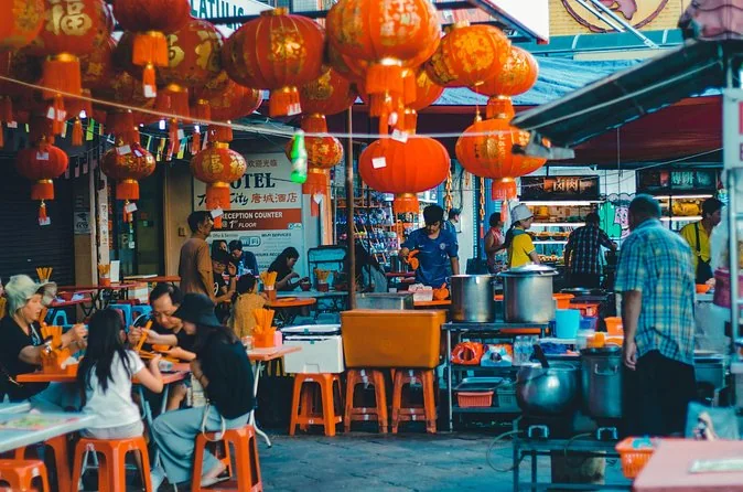 Street food stalls in Chinatown at dusk with people at tables under lights